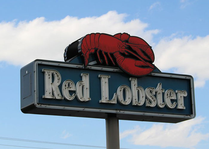 Red Lobster restaurant sign with a large red lobster figure against a blue sky, chain restaurant employees warn customers.