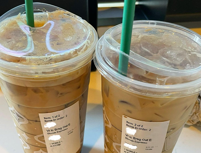 Two iced coffee drinks from a chain restaurant with green straws and order labels on the cups