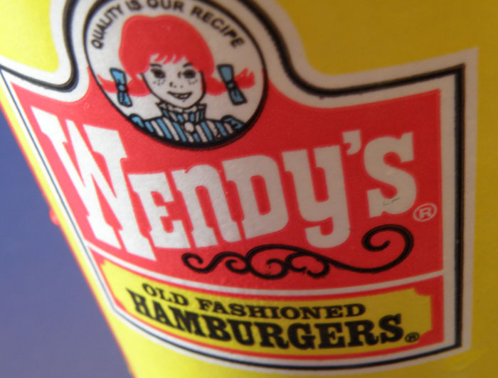 Close-up of a Wendy's cup featuring the logo, highlighting chain restaurant employees warnings on menu items.