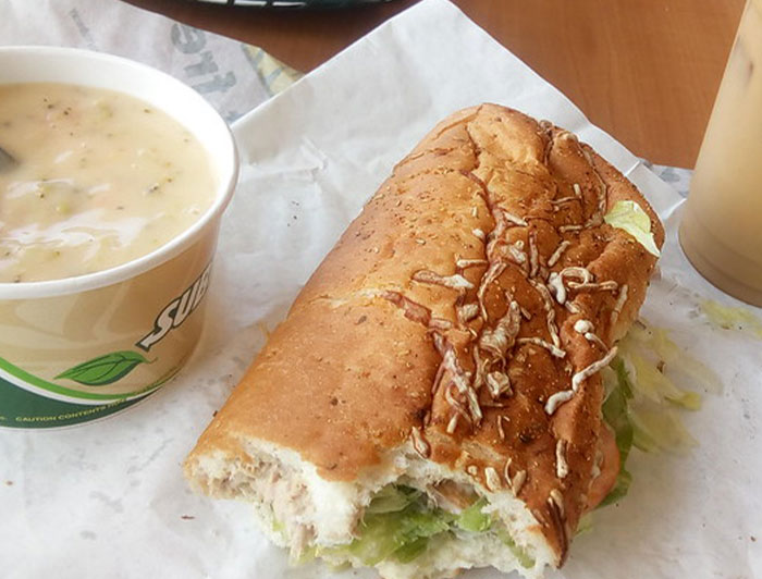Partially eaten sandwich and soup from a chain restaurant, illustrating items employees warn people not to order.