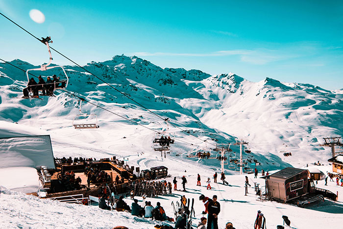 Ski resort scene with chairlifts and people enjoying winter activities, showcasing rich people behavior at luxury destinations.
