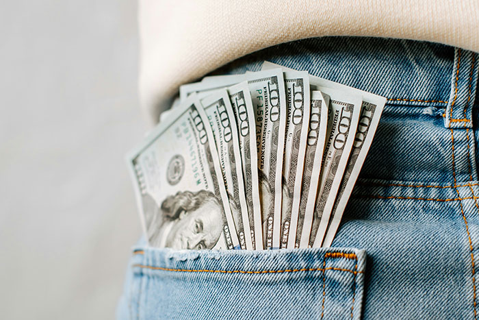 Cash in denim pocket illustrating rich people behavior and wild stories from high-end hotels and restaurants staff.