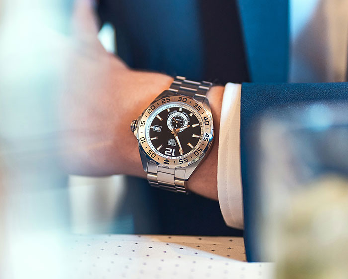 Luxury watch on wrist of a well-dressed person, illustrating rich people behavior in high-end settings