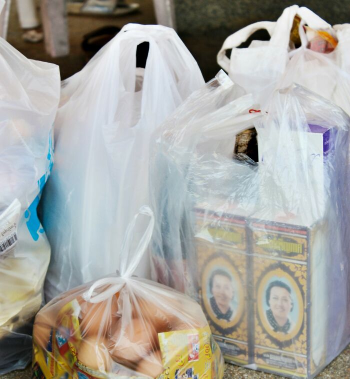 Plastic bags filled with groceries and packaged goods representing poor people habits in daily shopping routines.
