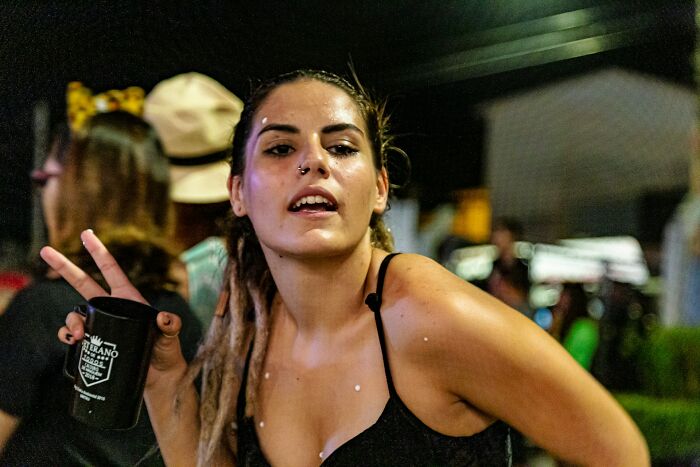 Young woman at a night event holding a cup, illustrating big no no to do in your country cultural behavior.