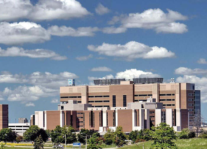 Large hospital building under a blue sky, related to man trapped in hospital for nine years exposing staff.