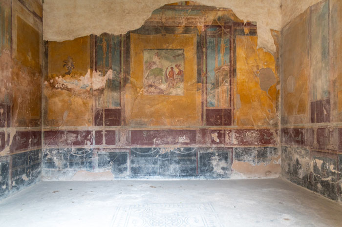 Ancient Roman comic paintings on walls showing humorous scenes from the empire in a faded historic room.
