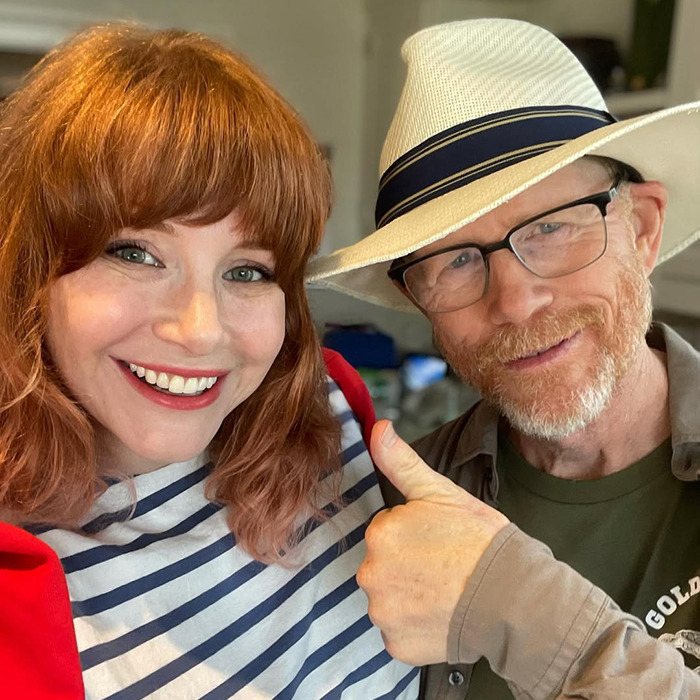 Bryce Dallas Howard and Ron Howard smiling together, highlighting nepotism and her challenging childhood experiences.