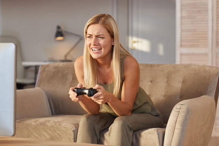 Young woman intensely gaming on a console during a late-night gaming marathon in a cozy living room.