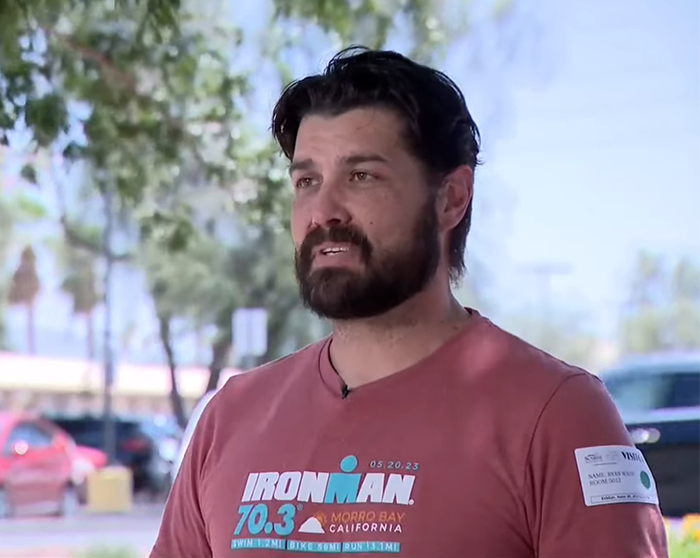 Man with beard and mustache wearing a red Ironman shirt outside, discussing terrifying words his hallucinating son said before cliff incident