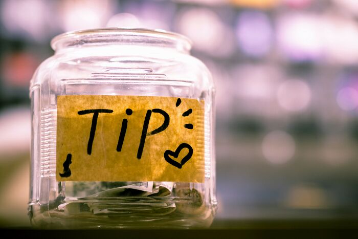 Glass tip jar with dollar bills inside and a handwritten label, symbolizing a priceless reward after spending just a dollar.