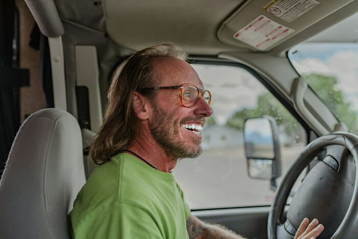 Man with glasses smiling inside a vehicle, capturing a memorable I was there when it was written moment.
