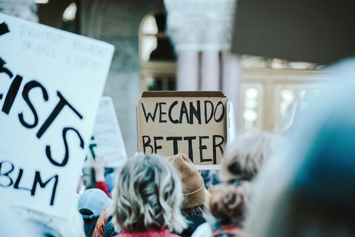 Crowd holding protest signs with messages, illustrating social hobbies that give netizens the ick faster than a bad date.