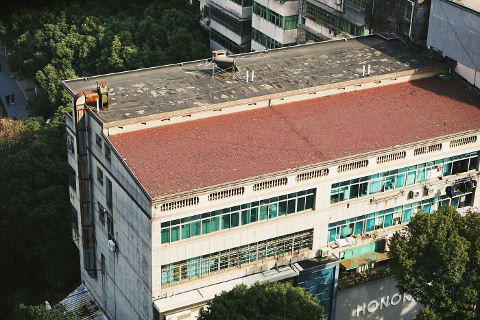 Aerial view of an abandoned building surrounded by trees, evoking eerie feelings linked to abandoned explorers.