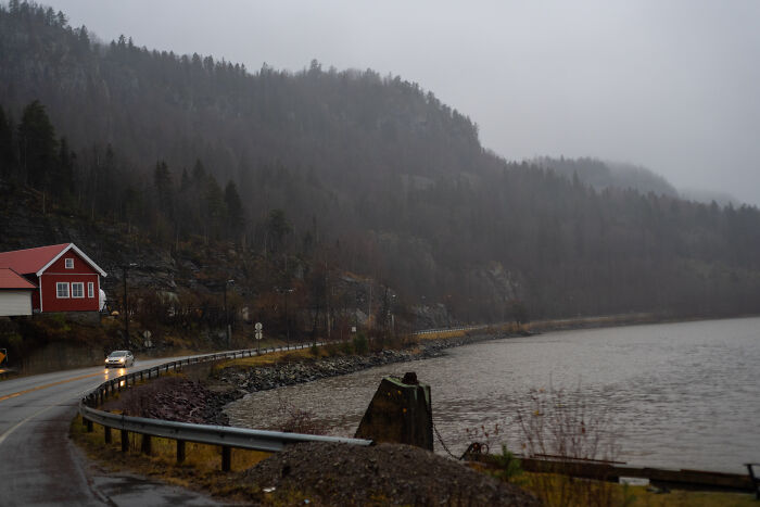 Foggy lakeside road with a red house and misty forested hills, illustrating European netizens correcting country misconceptions.