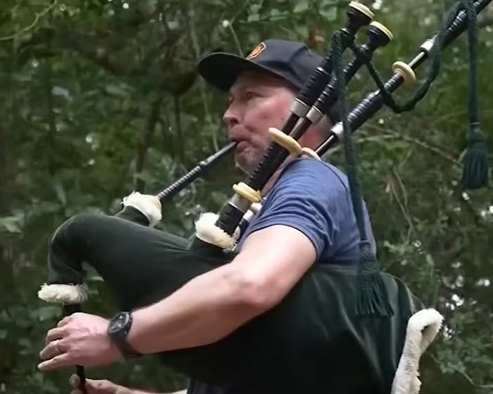 Man playing bagpipe outdoors in a park setting capturing the essence of bagpipe Karen incident and instant karma theme.