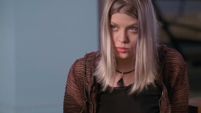 Young woman with blonde hair wearing a brown sweater, looking serious in a scene depicting tragic losses in TV shows.