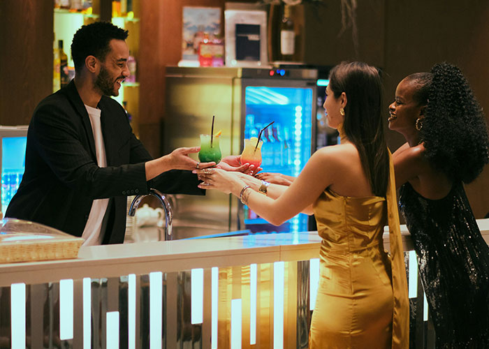 Bartender serving colorful alcoholic drinks to two women at a wedding bar during a dry wedding event.