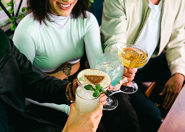 Group of friends clinking glasses with cocktails, illustrating secretly selling alcohol at a dry wedding to cover costs.