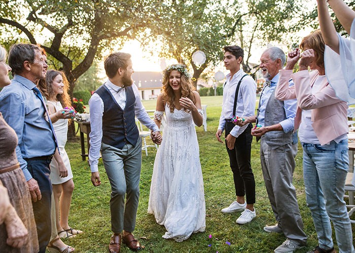 Bride and groom celebrating with guests at an outdoor wedding, secretly selling alcohol at a dry wedding to cover costs