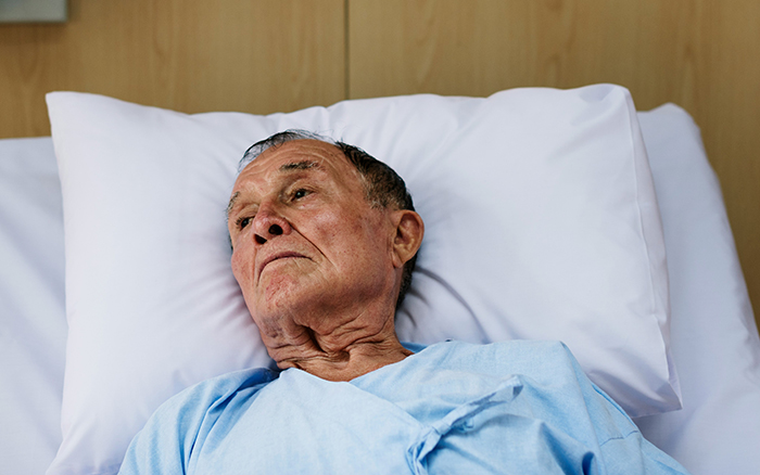 Elderly man lying in hospital bed looking thoughtful, reflecting themes of disturbing deathbed confessions and guilt.
