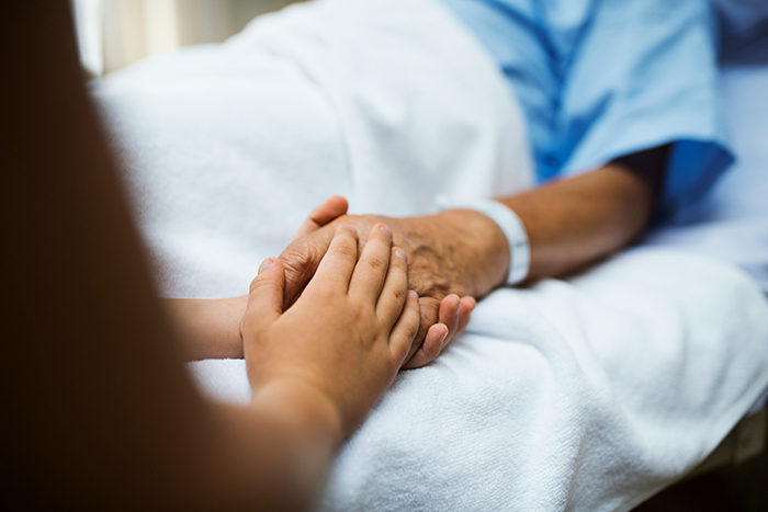 Close-up of two people holding hands in a hospital bed, symbolizing guilt and deathbed confessions support.