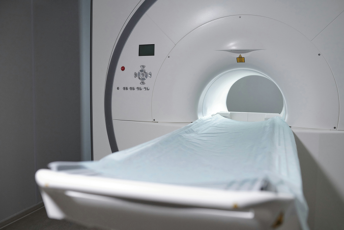 MRI machine with patient bed covered in a sheet, symbolizing medical settings related to disturbing deathbed confessions.