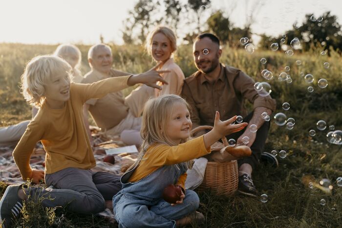 Family enjoying an outdoor picnic with children playing and capturing joyful moments of emotional confessions and heavy secrets.