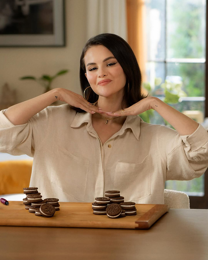 Selena Gomez posing with stacks of Oreo cookies, highlighting Oreo's new Selena Gomez flavored snack in a cozy setting. Selena Gomez posing with stacks of Oreo cookies, highlighting Oreo's new Selena Gomez flavored snack in a cozy setting.