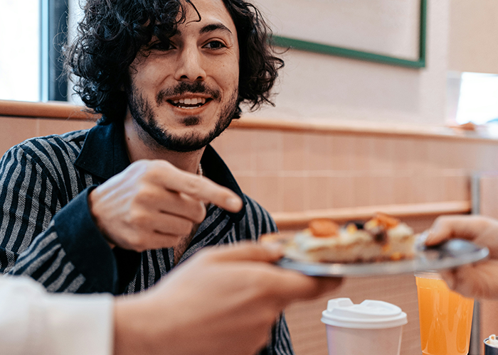 Man in striped shirt offering a plate with a twist on classic chicken pot pie during a family gathering meal.