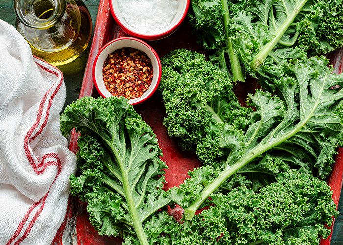 Fresh kale leaves on a tray with chili flakes and oil, ingredients for a unique chicken pot pie recipe twist.