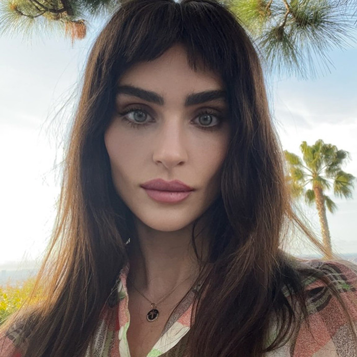 Sharon Osbourne&rsquo;s rarely-seen daughter posing outdoors with long hair and natural makeup amid palm trees background