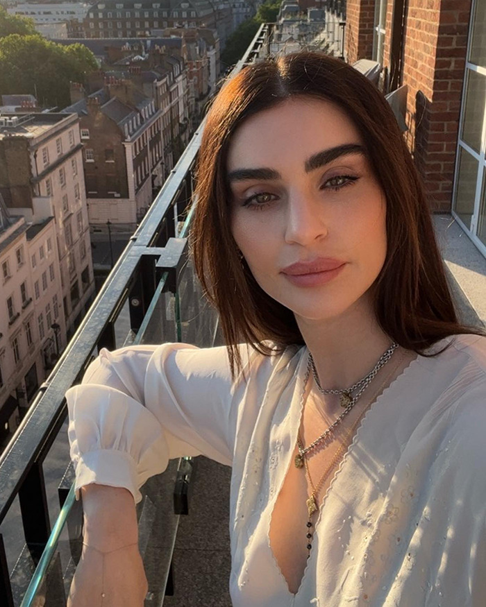 Sharon Osbourne's daughter posing on balcony showing new look amid Ozempic use rumors in natural sunlight.