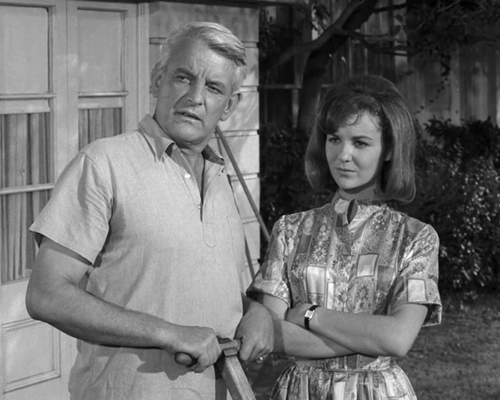 Black and white photo of iconic sitcom legend with a young woman, both standing outdoors in vintage clothing.