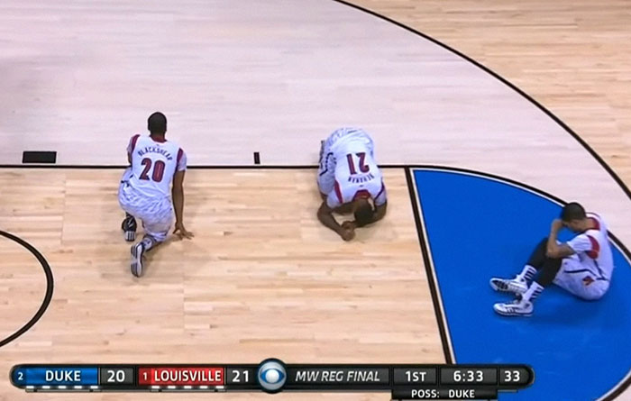 Three basketball players from Louisville reacting on court during a shocking live television moment in the MW regional final.