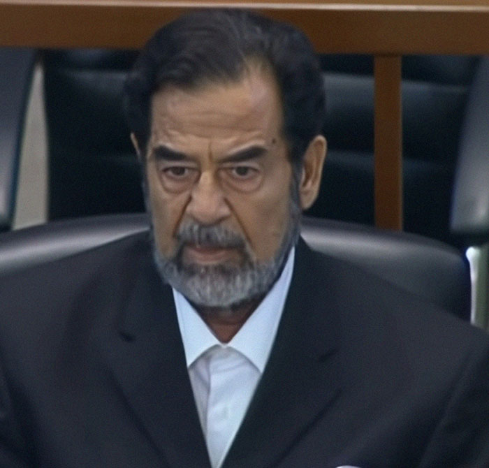 Middle-aged man with beard and dark suit seated, captured during a shocking live television moment for Gen X viewers.