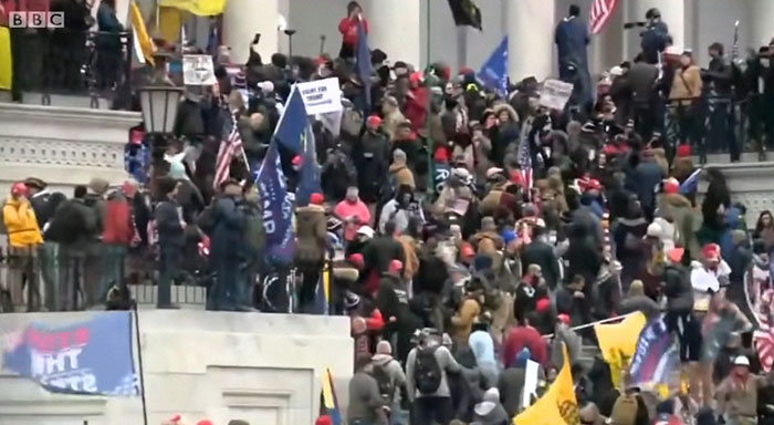 Crowd gathered on building steps holding flags and signs during one of the most shocking moments on live television.