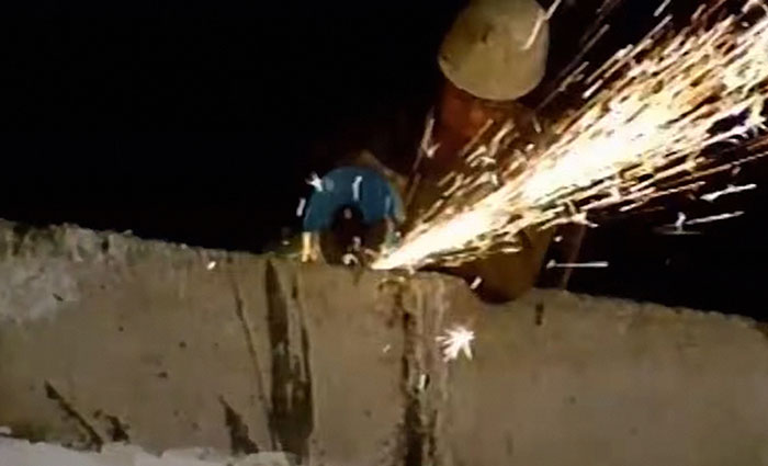 Worker wearing helmet cutting metal on a live television broadcast causing sparks during shocking Gen X moments.
