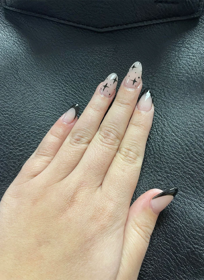 Hand with short French tip nails featuring black star designs, showcasing a stylish nail art trend for 2025. Hand with short French tip nails featuring black star designs, showcasing a stylish nail art trend for 2025.