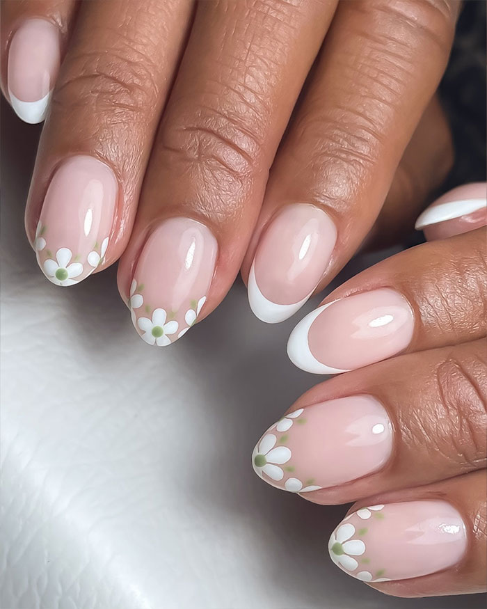 Close-up of short French tip nails with floral design featuring white tips and daisy patterns on polished natural nails. Close-up of short French tip nails with floral design featuring white tips and daisy patterns on polished natural nails.