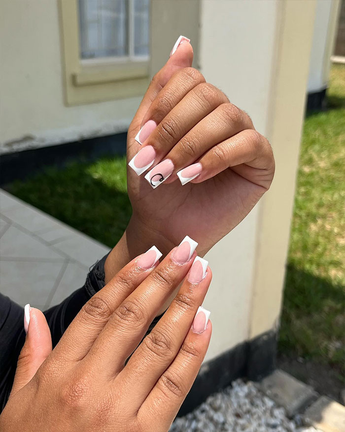 Short French tip nails with minimalist design on natural nails shown in natural light outdoors. Short French tip nails with minimalist design on natural nails shown in natural light outdoors.