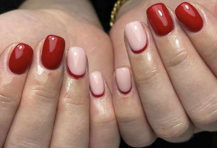 Short French tip nails with red and nude polish design on square-shaped nails, showcasing stylish nail art trends. Short French tip nails with red and nude polish design on square-shaped nails, showcasing stylish nail art trends.