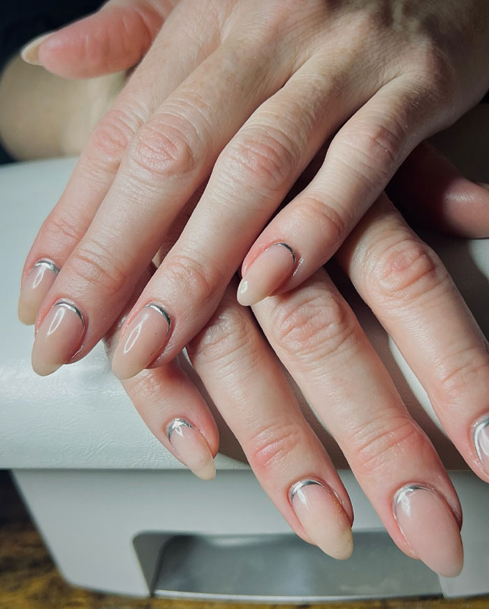 Hands with short French tip nails featuring a modern design, showcasing stylish nail art trends in 2025.