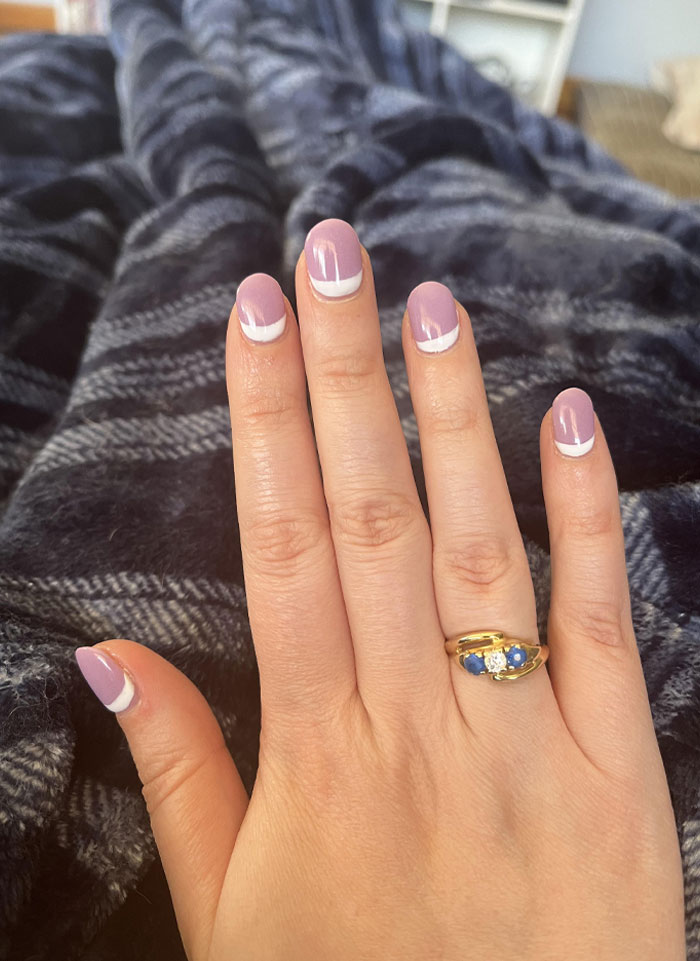 Hand with short French tip nails in purple and white design, showcasing stylish nail art trends for 2025. Hand with short French tip nails in purple and white design, showcasing stylish nail art trends for 2025.