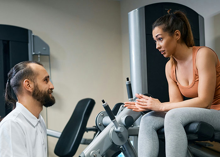 Woman at gym telling guy she is not here to make friends while he tries to fist bump her during workout session