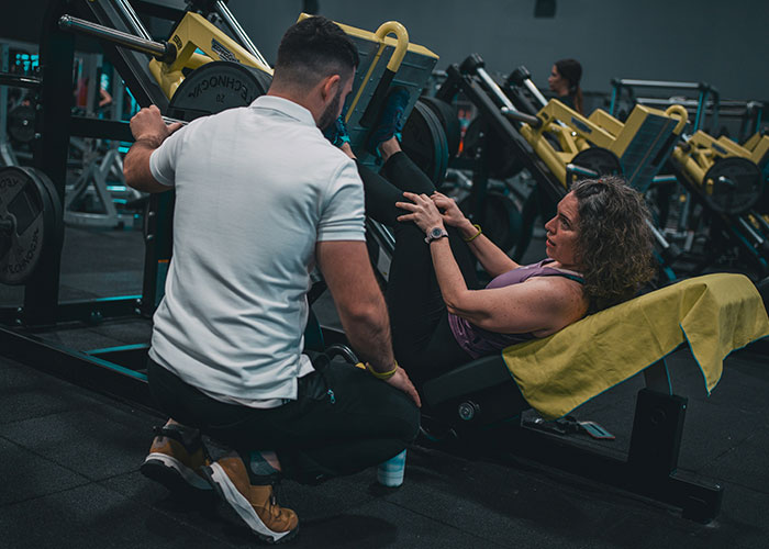 Woman and gym guy interacting during leg press workout, highlighting gym social dynamics and fitness training.