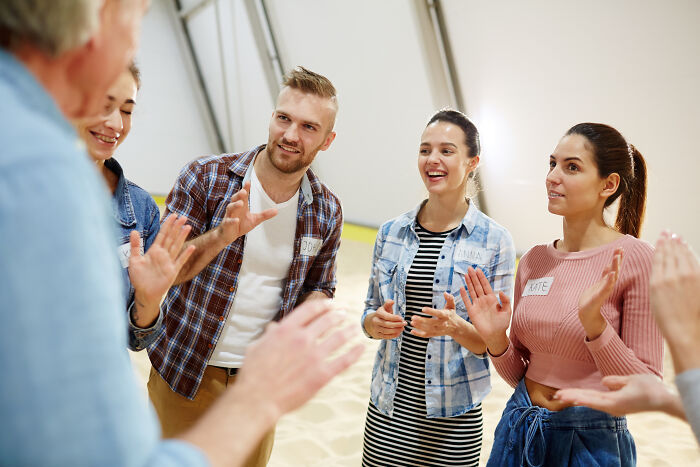 A group of young adults interacting and smiling in a casual setting, illustrating being shy making social situations harder.