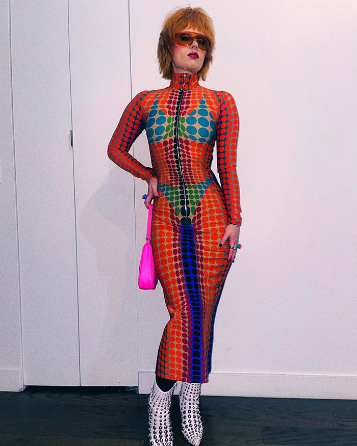 Person in a colorful patterned dress and sunglasses, showcasing child star's unrecognizable transformation and bold style.