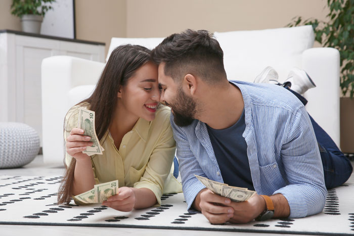 Couple counting money on floor in living room, illustrating themes of greed and family conflict over new house. Couple counting money on floor in living room, illustrating themes of greed and family conflict over new house.