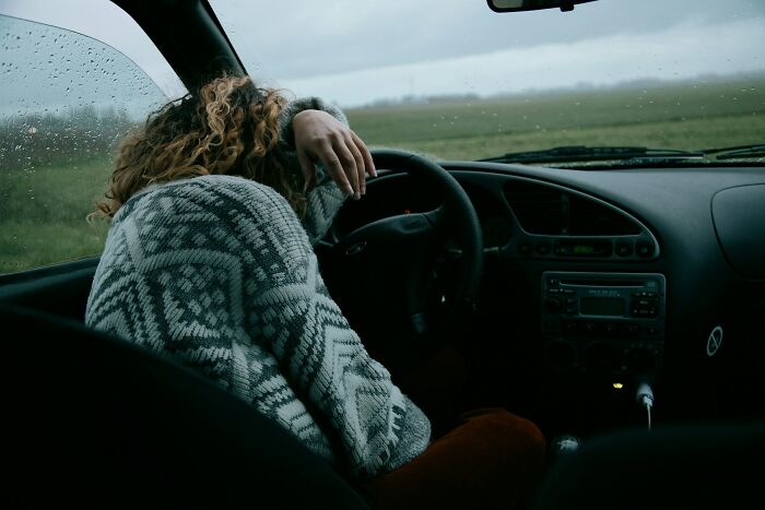 Woman sitting in a car with head resting on the steering wheel, illustrating frustration with dismissive doctors.